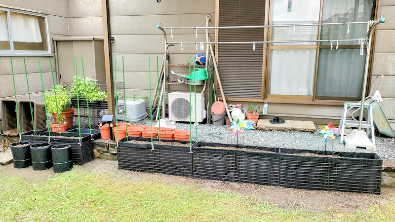 家庭菜園に並べて設置した黒い手作り深型プランター